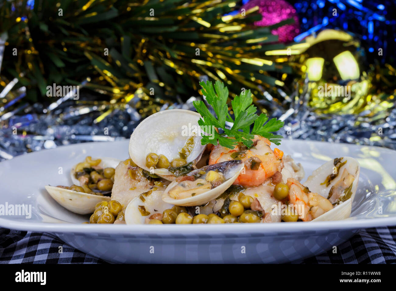 Hake in clam sauce with prawns and peas at Christmas. Stock Photo