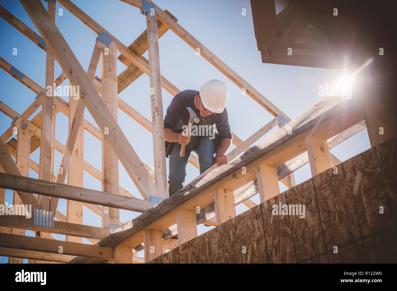 Builder working on rooftop frame of building Stock Photo