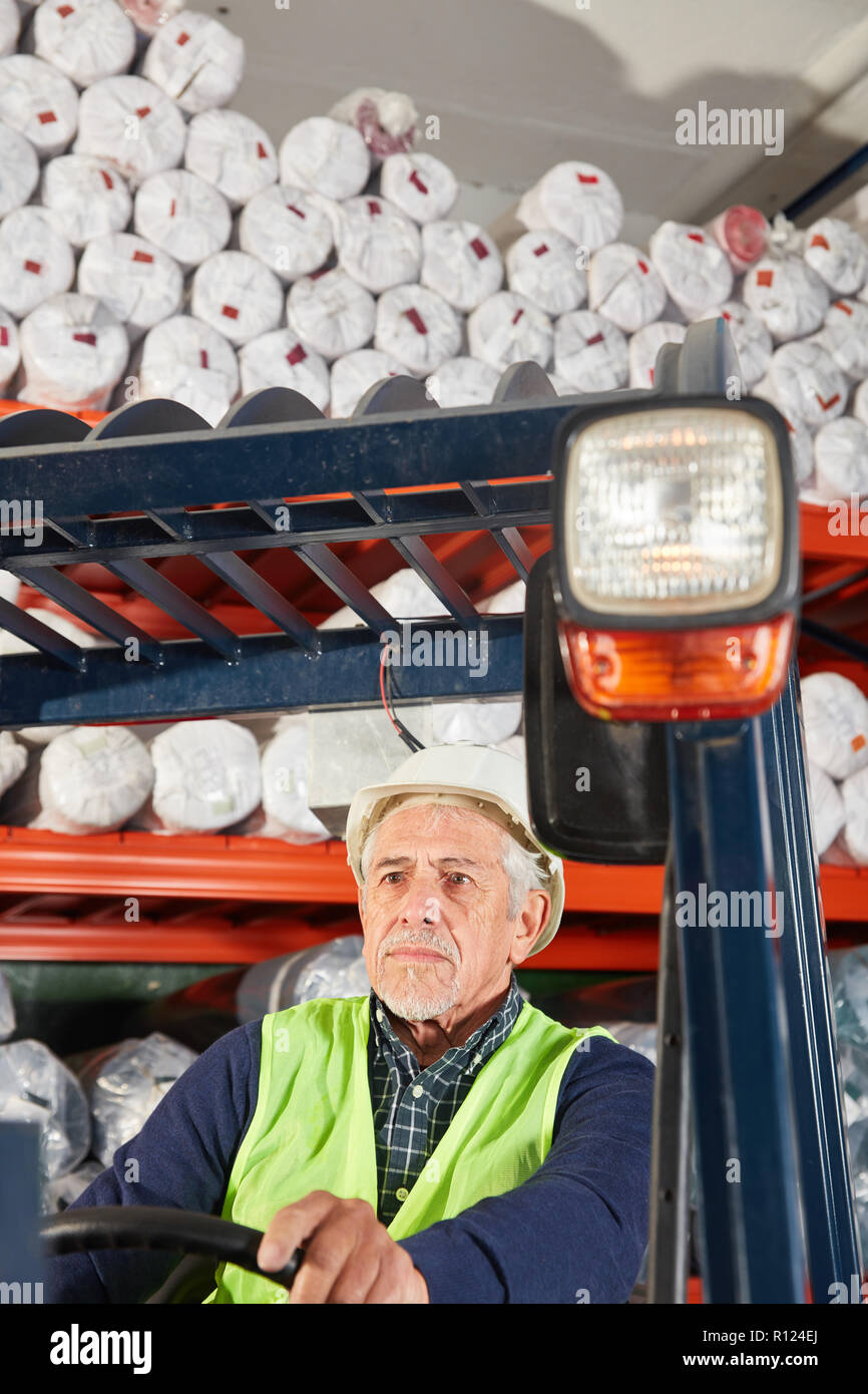 Worker as a forklift driver on the forklift in the warehouse at work Stock Photo