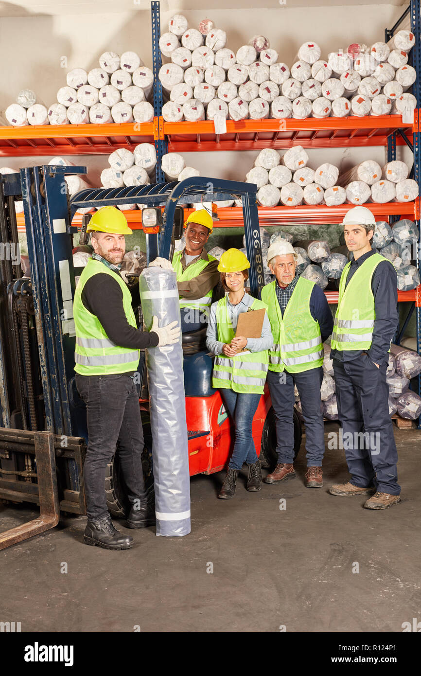 Group of warehouse workers as a team with forklift in hall in shipping