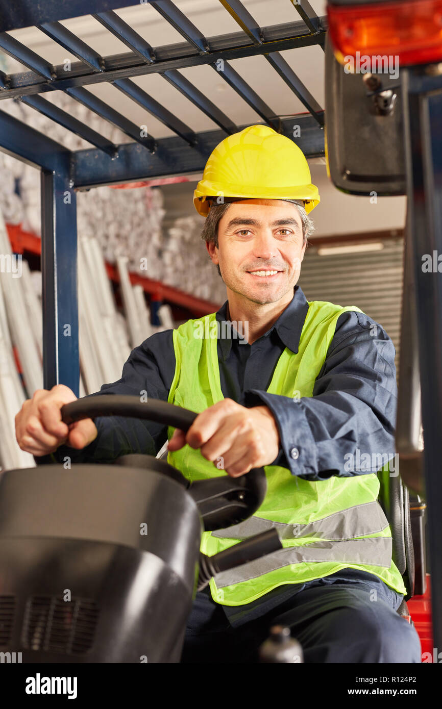 Smiling warehouse worker as a forklift driver transports freight in