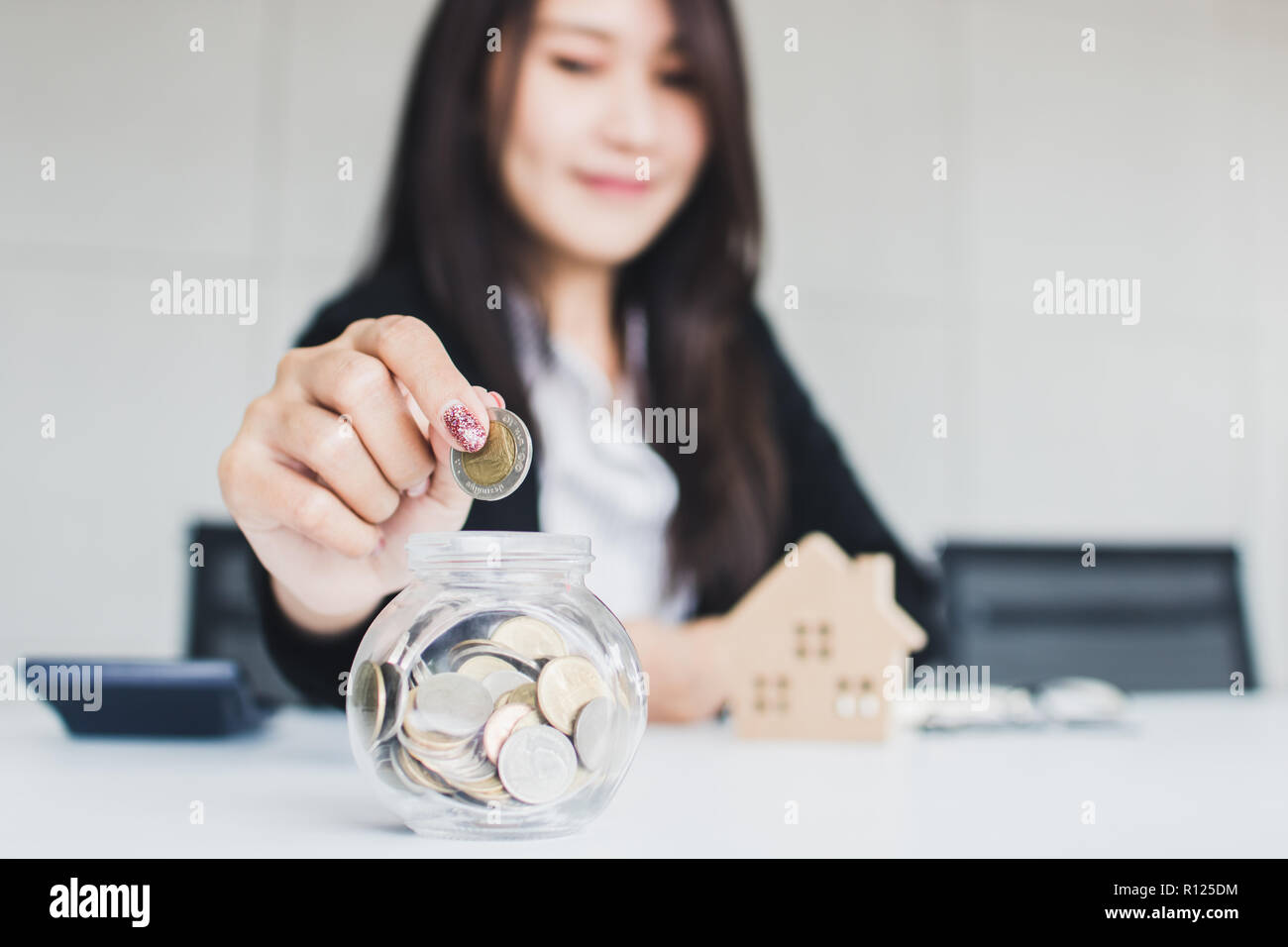 Banker introduces cheap interest for buying residence concept, business woman saving money in glass of jar to get home, housing loan. Stock Photo