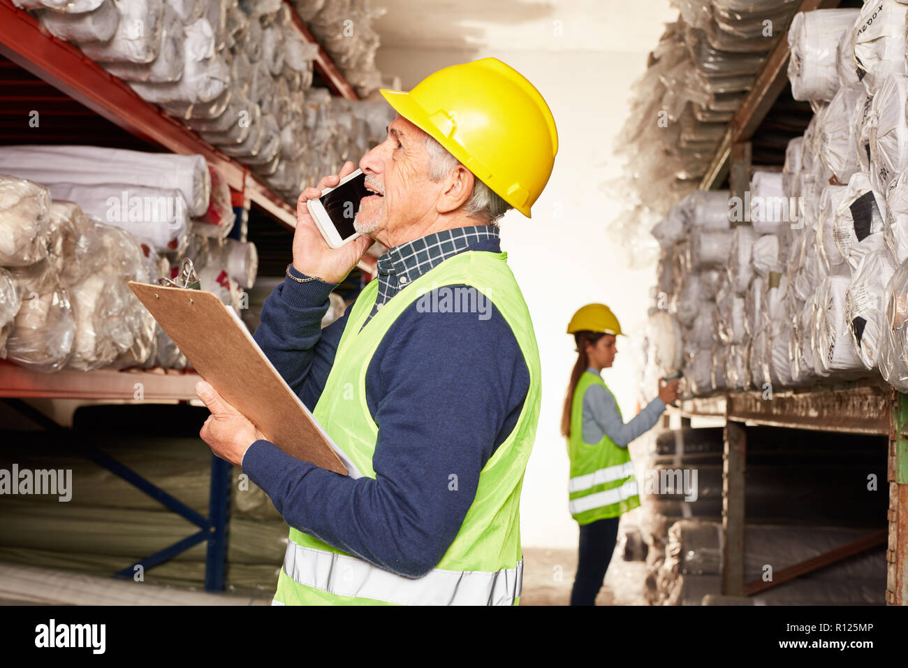 Senior worker in the warehouse in the carpet warehouse is talking on