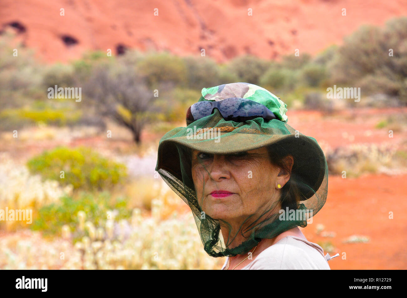 Brunette woman in the outback of Australia protected with a mosquito net over hat and head. Stock Photo