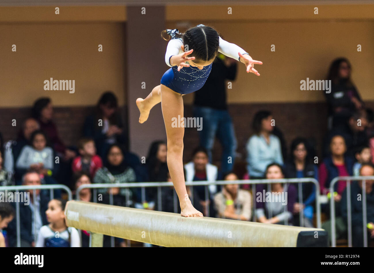 Young female gymnast performing handstand on balance beam, side view Stock Photo