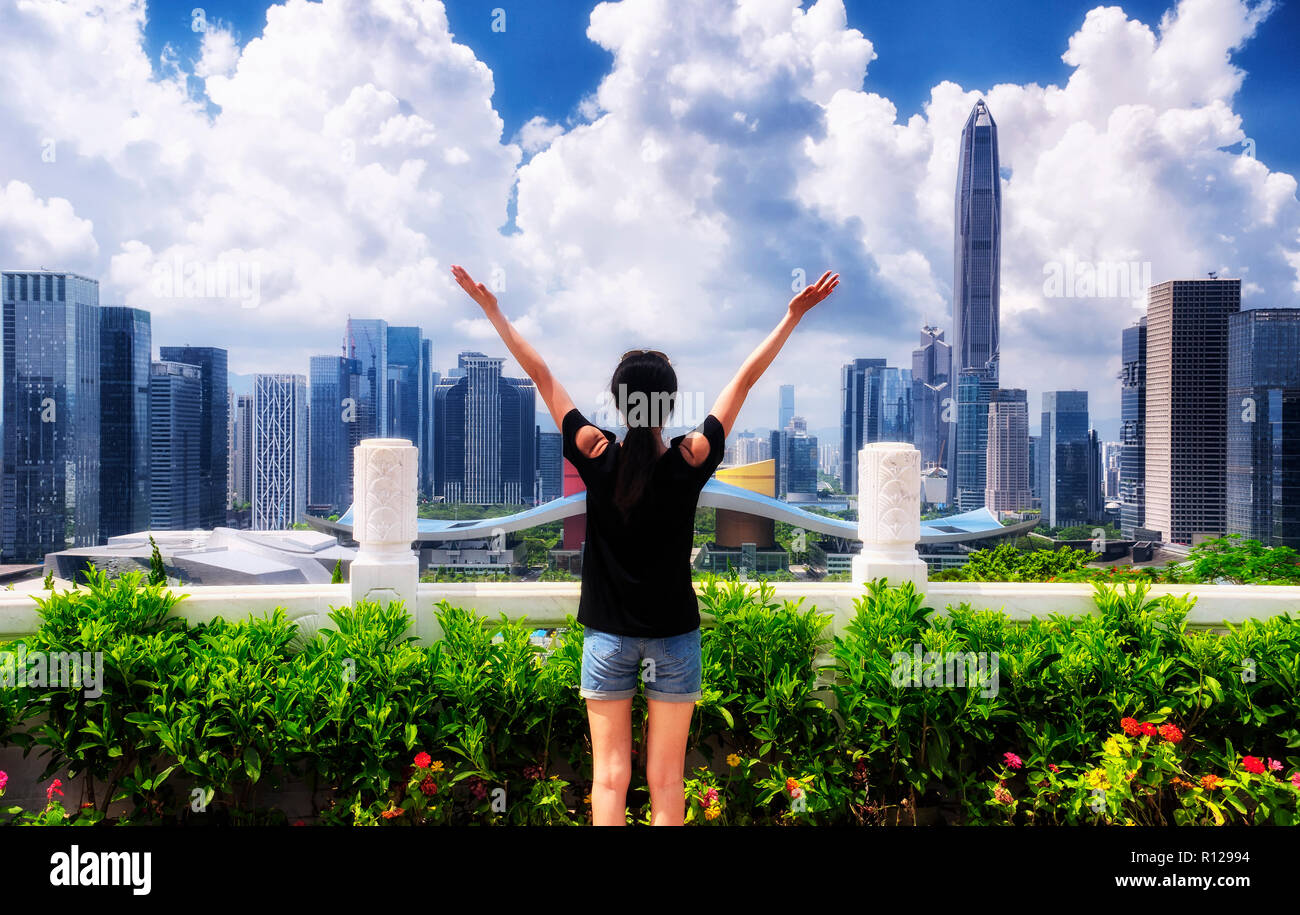 A chinese woman looking out over the city of Shenzhen China on a sunny