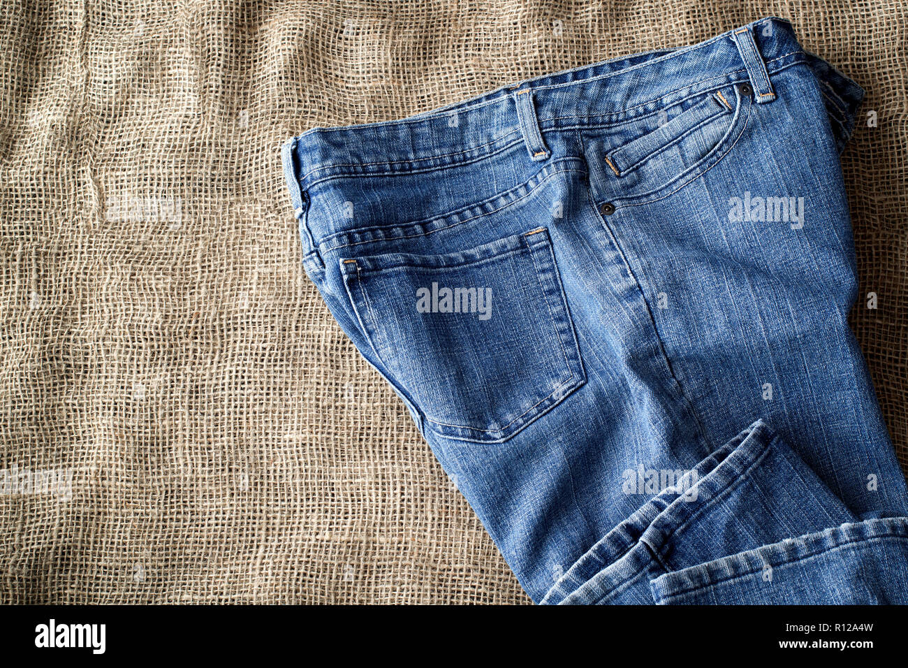 Blue jeans on burlap. Top down view. Stock Photo