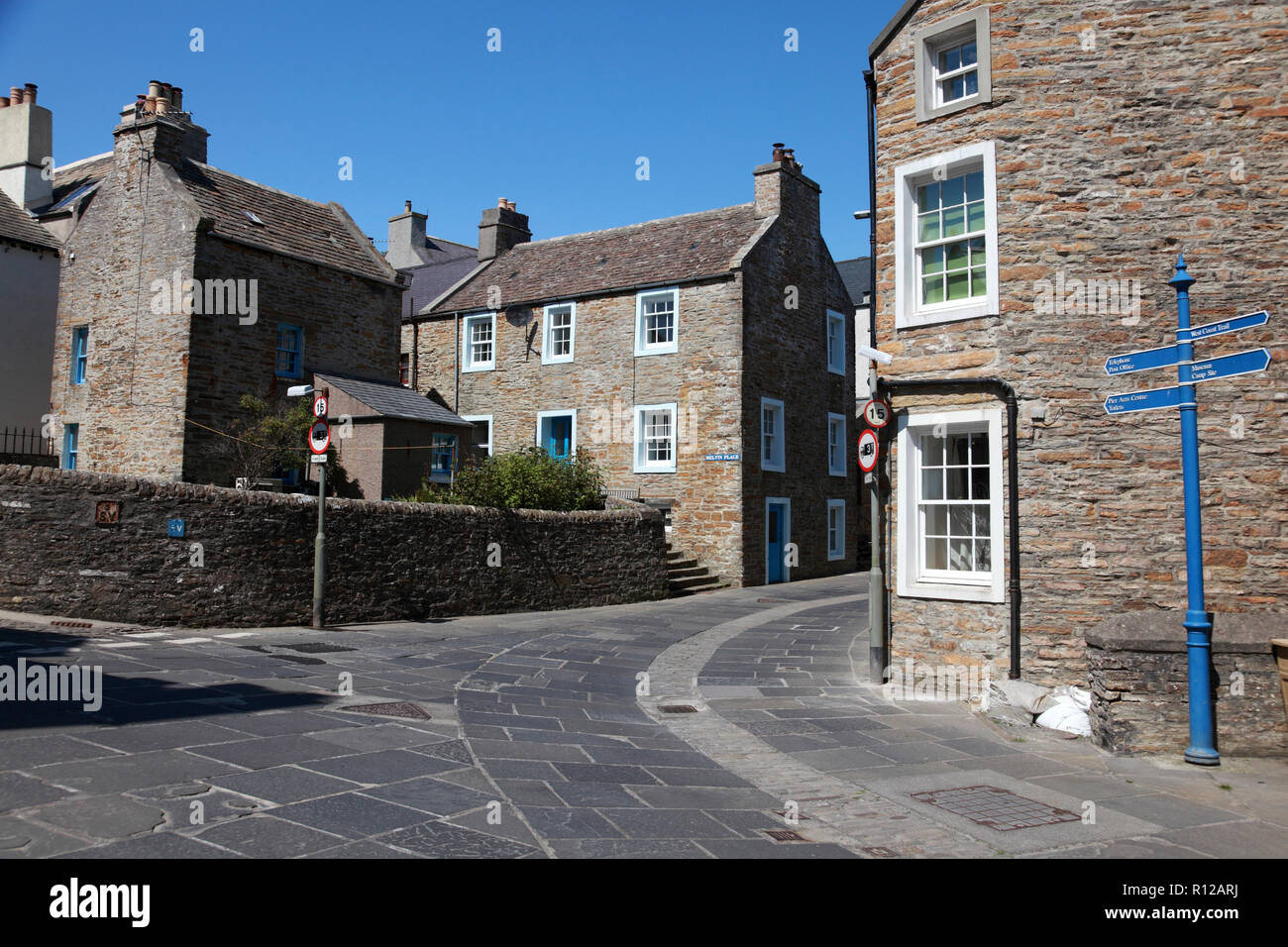 Old sandstone houses in Stromness, Orkney with paving stones from a local quarry and cobble stones in the centre of the street. Stock Photo