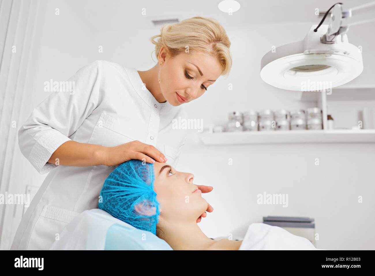 A female cosmetologist examines the face of a girl. Stock Photo