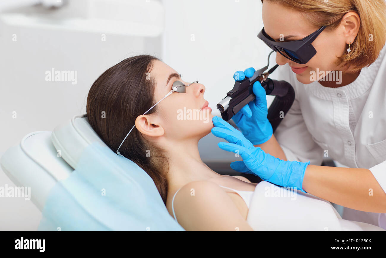 Laser hair removal on the face of a young woman in a cosmetology Stock Photo
