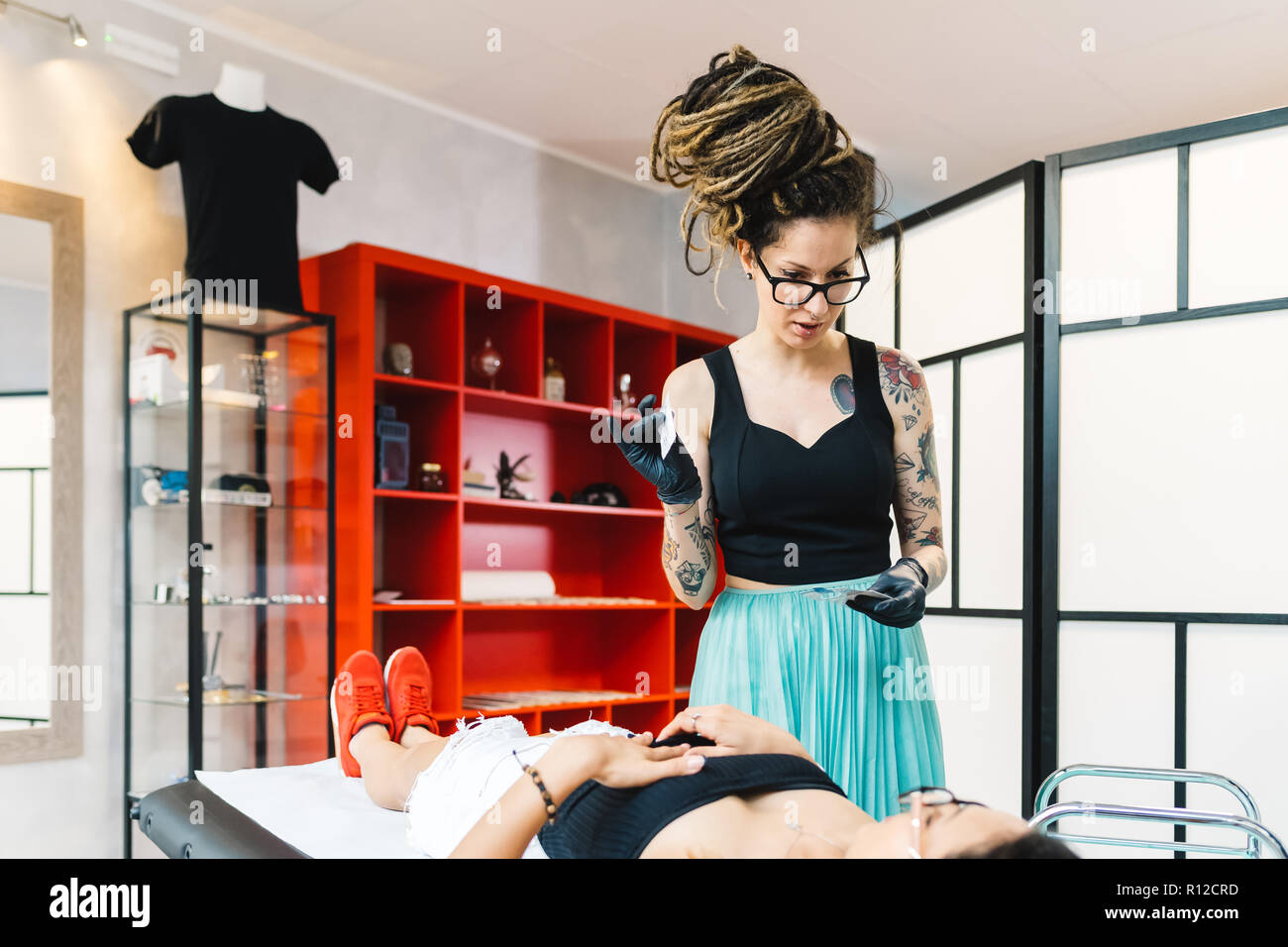 Tattooist attending to customer in parlour Stock Photo