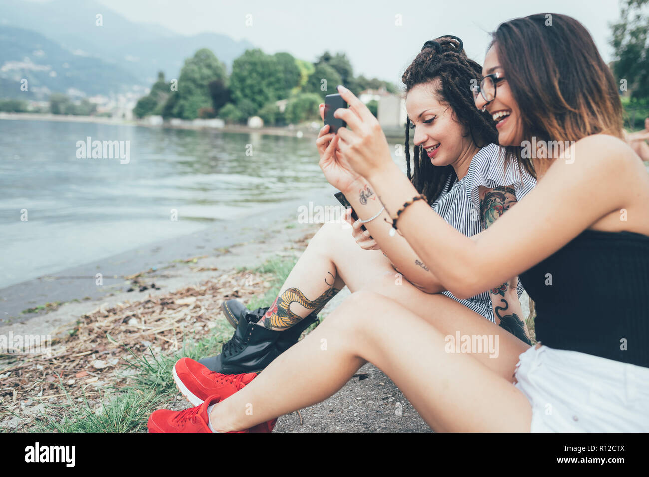 Girlfriends using mobile phone on beach Stock Photo