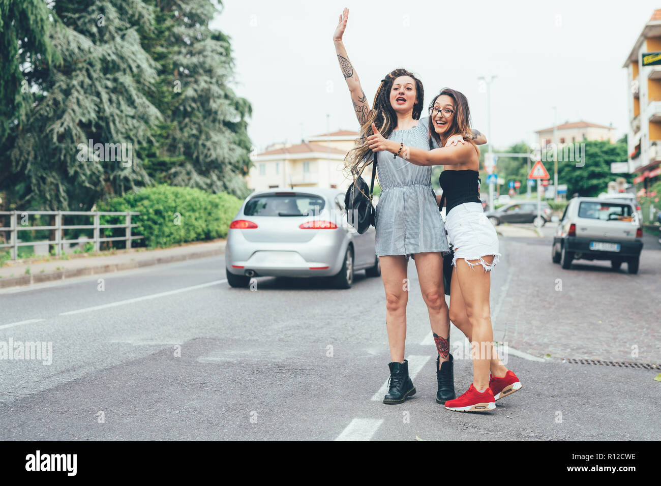 Girlfriends hailing cab in middle of road Stock Photo
