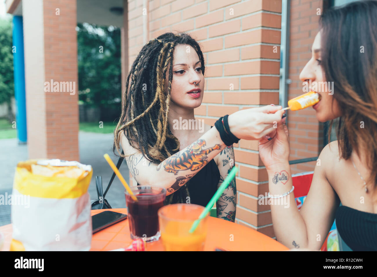 Girlfriends sharing ice cream at cafe Stock Photo