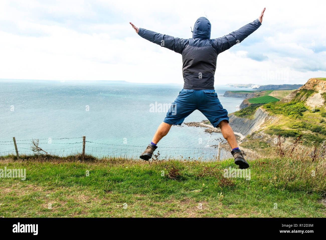 Man jumping on clifftop by sea, Bournemouth, UK Stock Photo