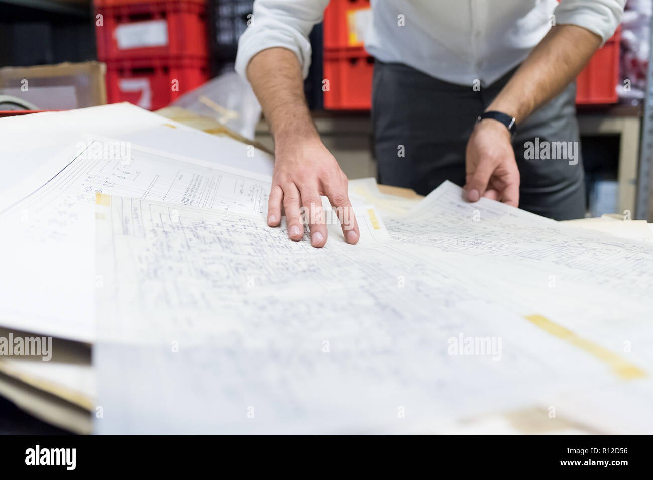 Man working on charts and plans in warehouse Stock Photo