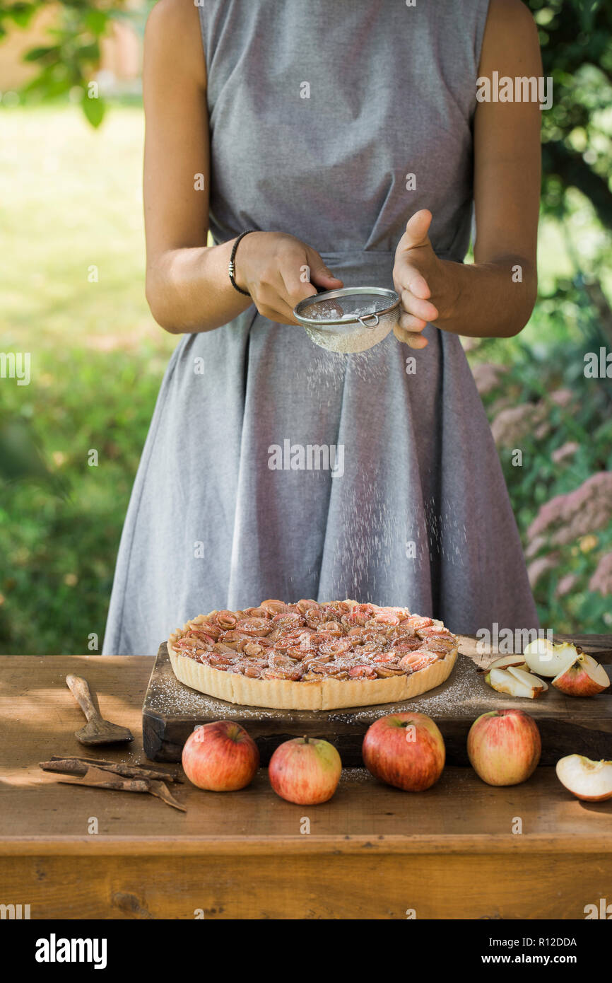 Woman preparing apple pie on table Stock Photo