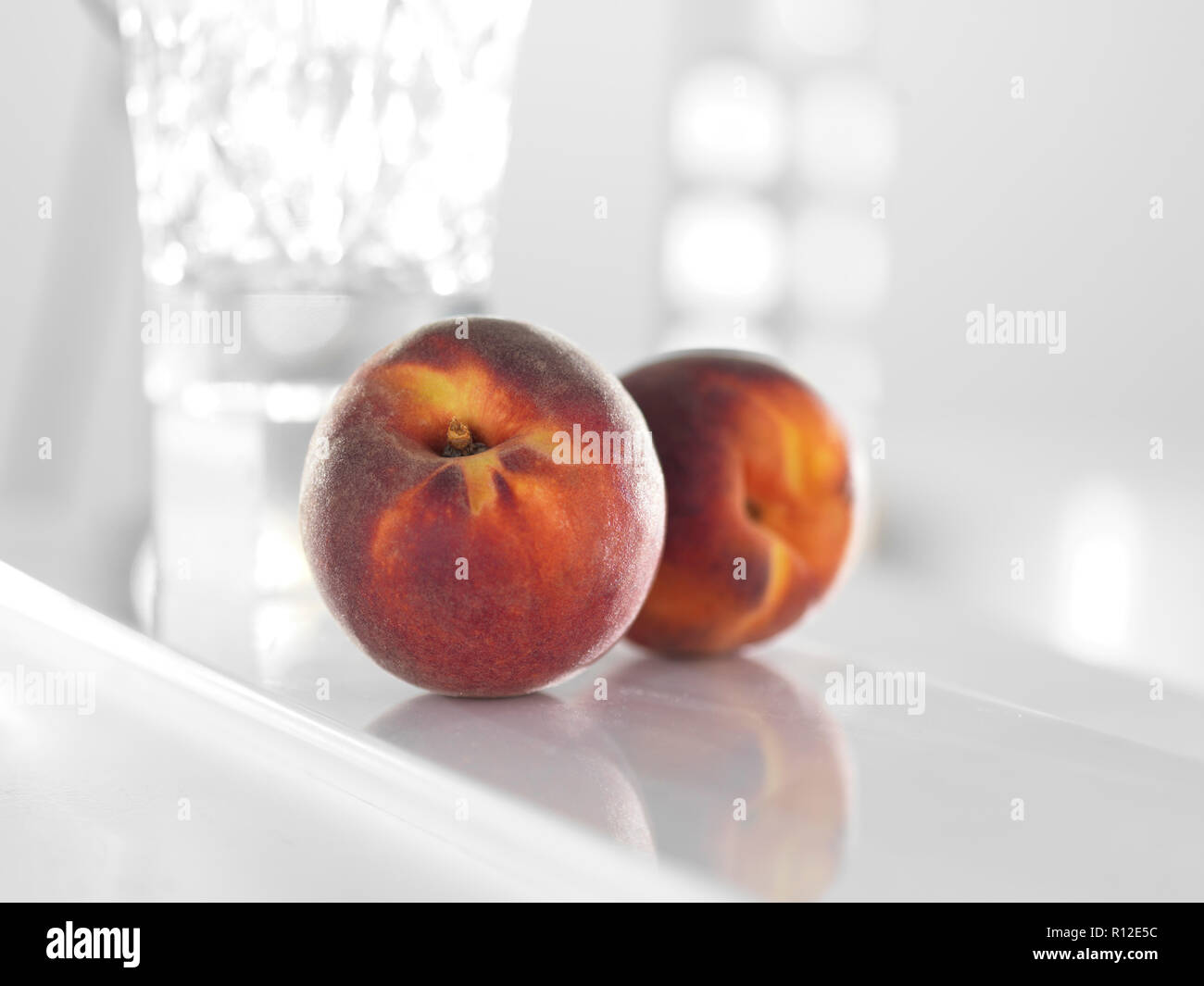 Peaches on glossy white surface Stock Photo