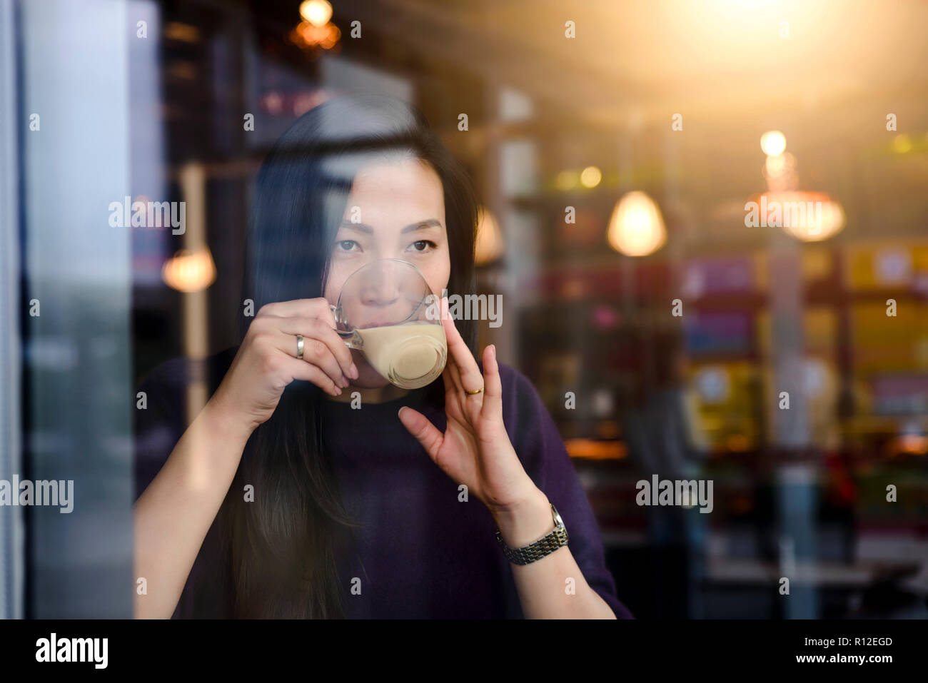 Mid adult woman drinking coffee in cafe window seat Stock Photo