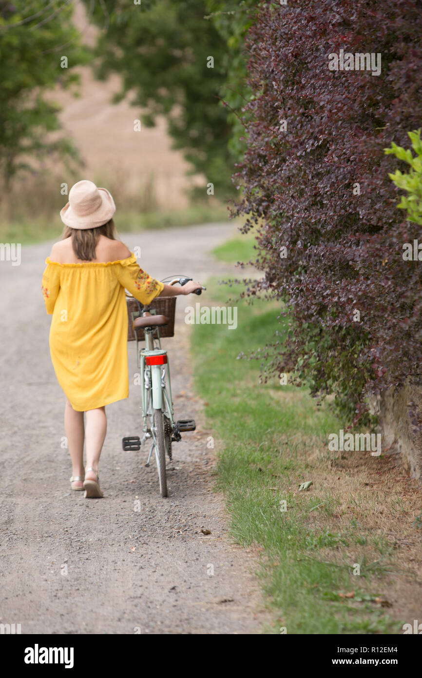Woman walking bicycle in countryside Stock Photo