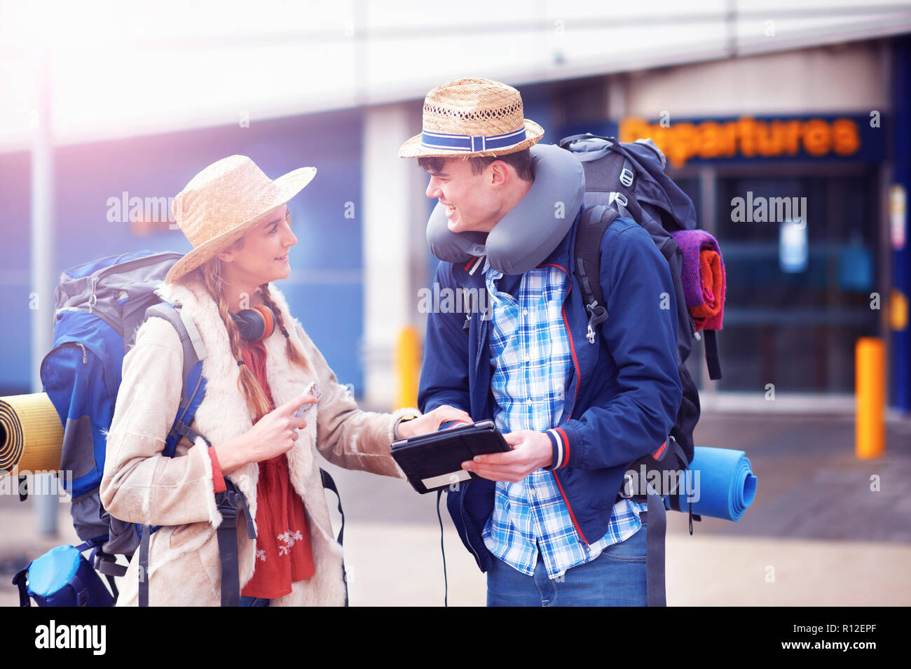 Backpacker couple using digital tablet at airport Stock Photo