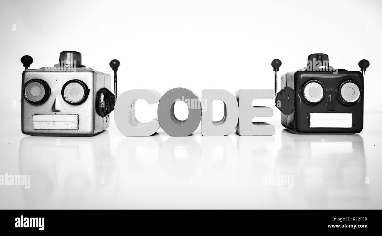 two retro robot head on white with the word CODE with wooden letters Stock Photo