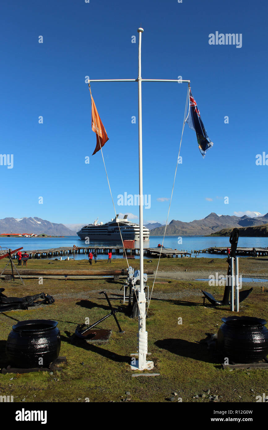 Masthead, flags, try pots and expedition ship outside the museum at Grytviken, former whaling station, King Edward Cove, South Georgia South Atlantic. Stock Photo