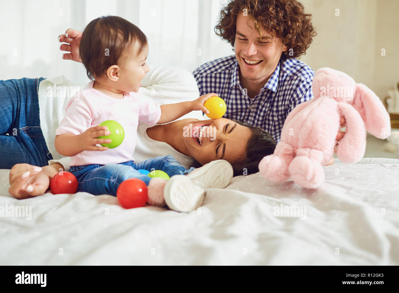 Happy family playing with the baby in the room. Young mother and Stock Photo