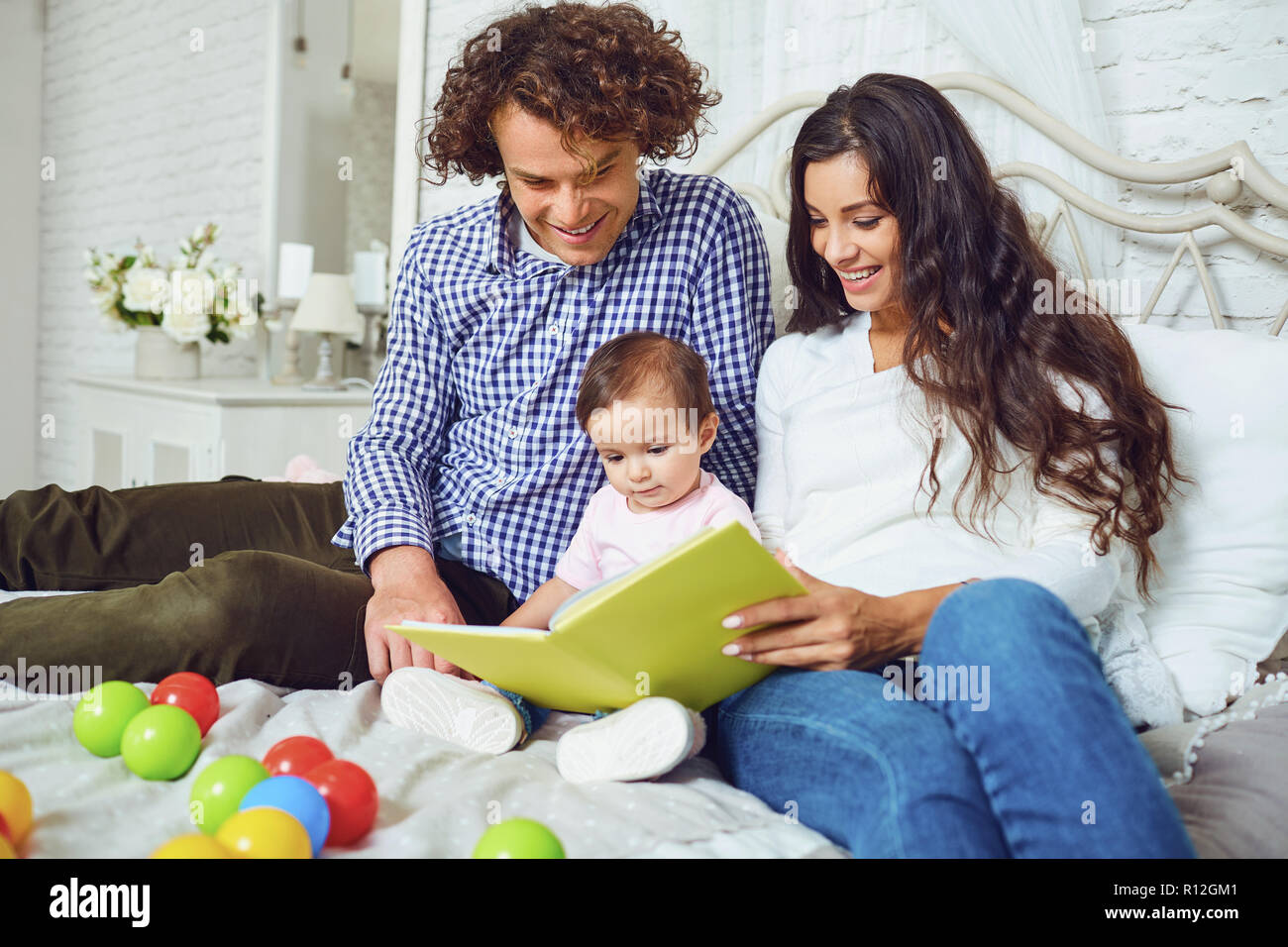 Happy family is reading a book with a child in the room.  Stock Photo