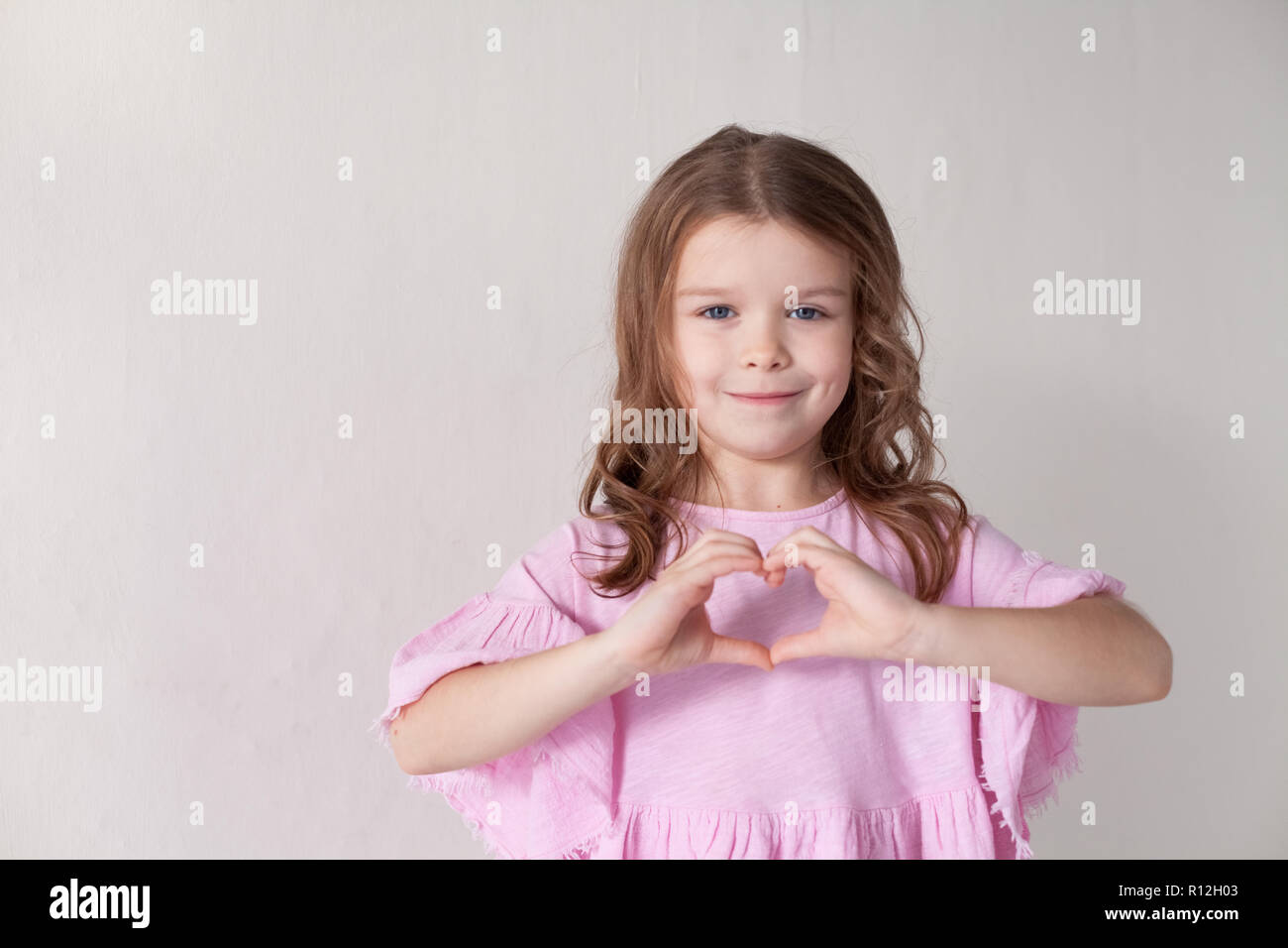 a little girl in a pink dress shows hands heart Stock Photo - Alamy