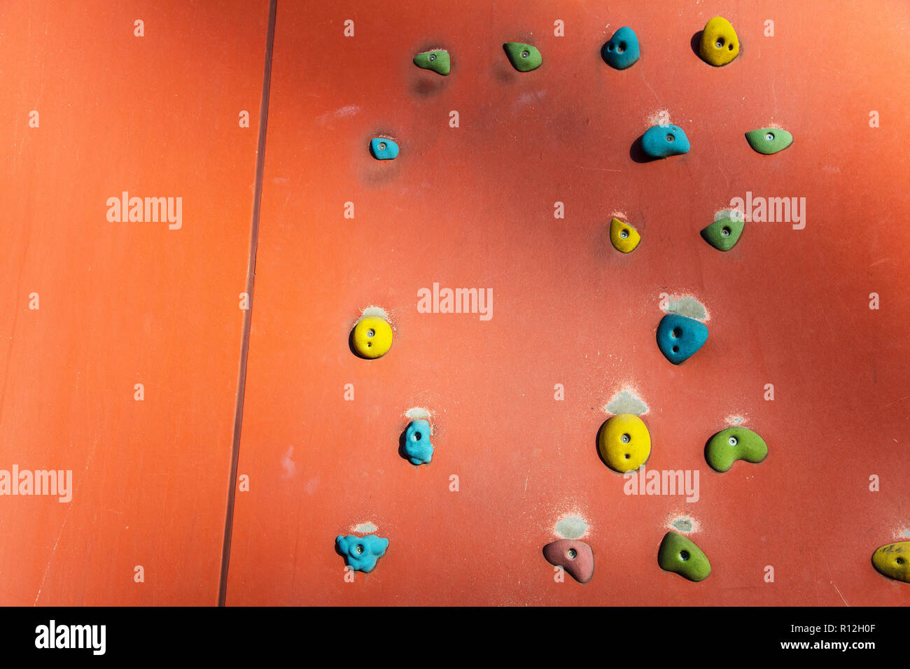 Rock climbing or Bouldering wall with colourful hand holds Stock Photo