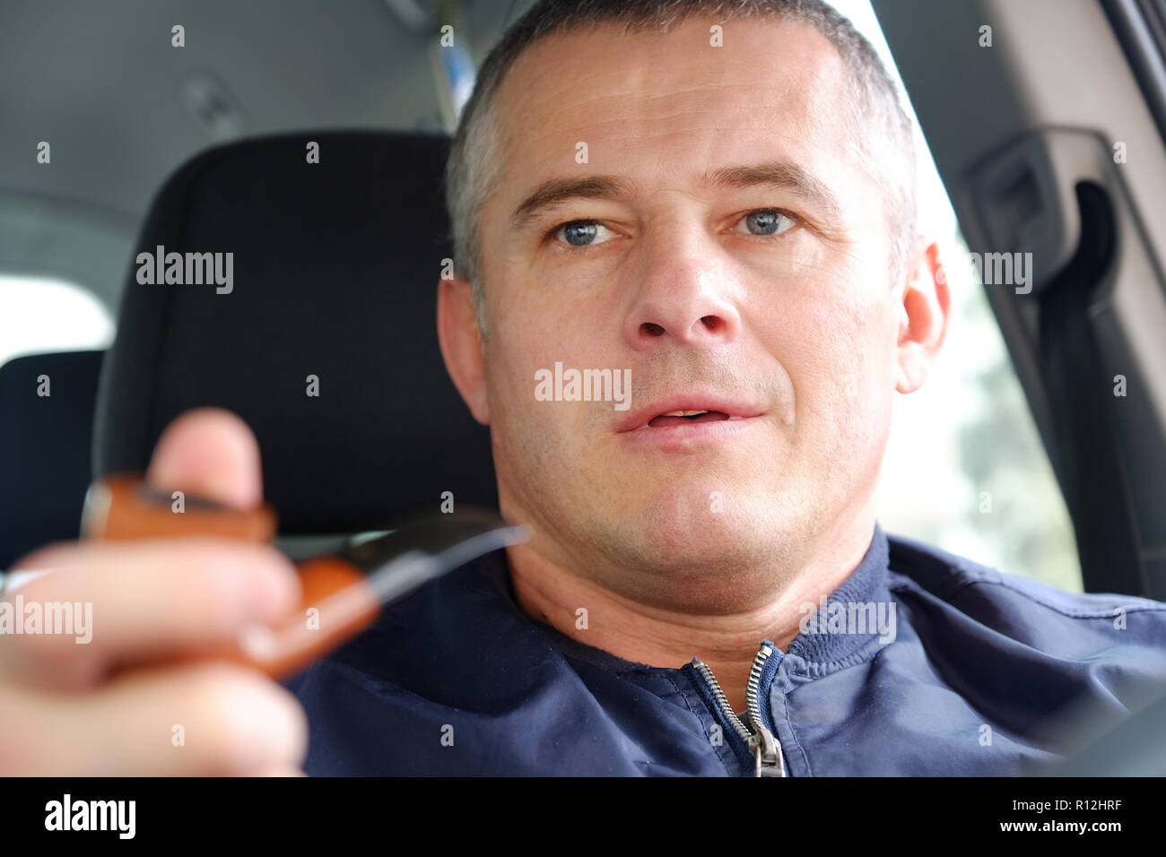 The man in the car driving. Tobacco pipe in hand. Stock Photo