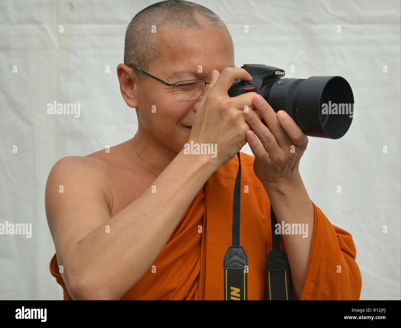 Thai Buddhist monk takes a photo with his brand-new Nikon D5500 DSLR camera. Stock Photo