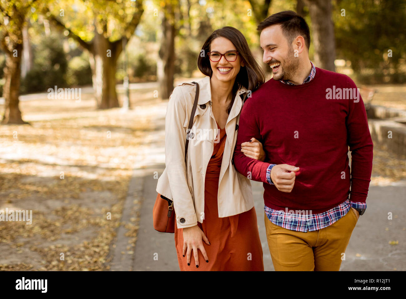 Loving young woman and man walking in city park holding hands Stock ...