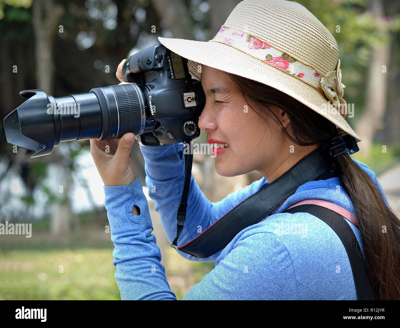 Female Vietnamese professional portrait photographer takes an outdoor portrait photo with her Canon EOS 7D DSLR camera. Stock Photo