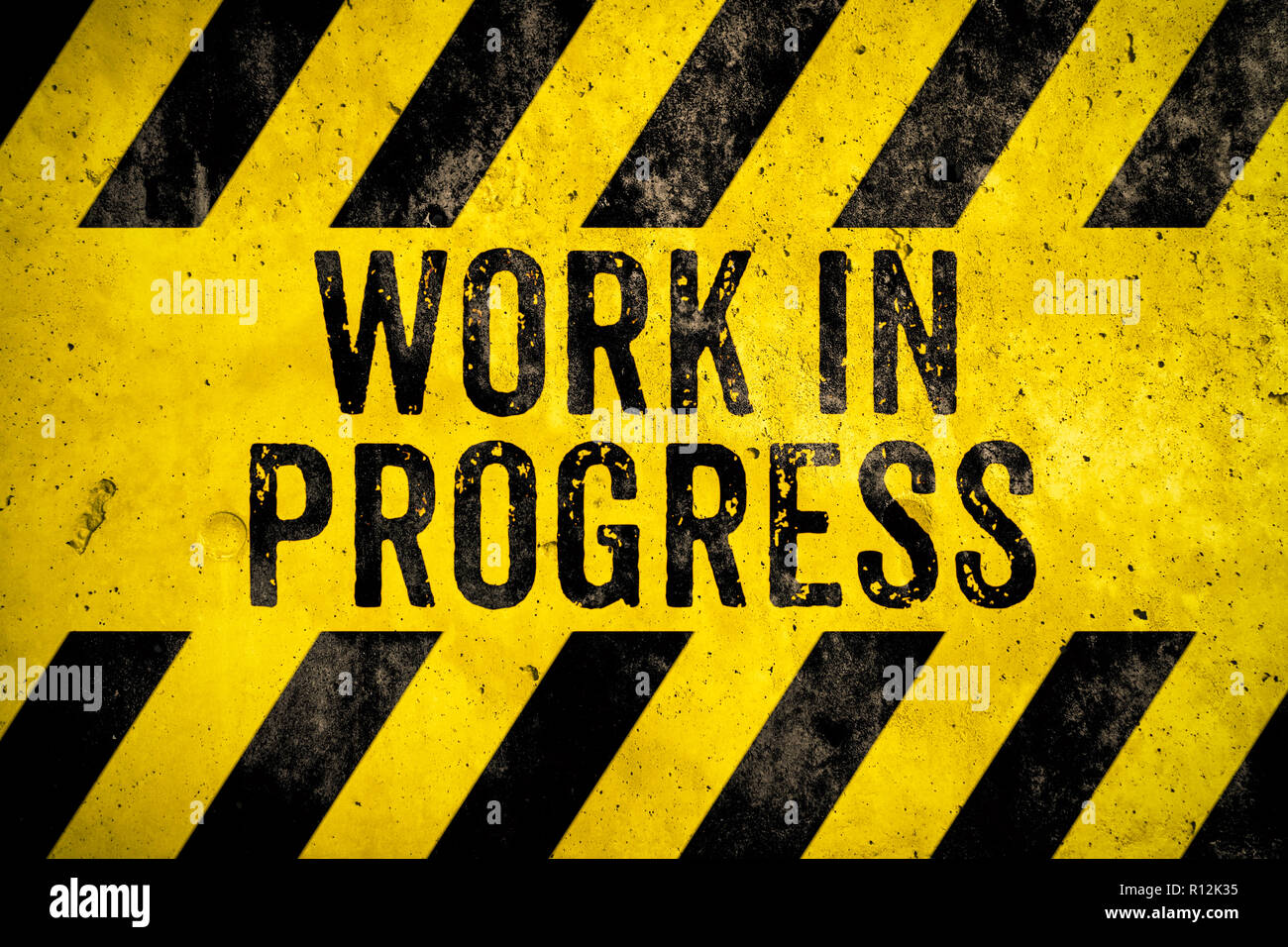 Work in progress warning sign text with yellow and black stripes painted over concrete wall cement texture background. Concept for do not enter the ar Stock Photo