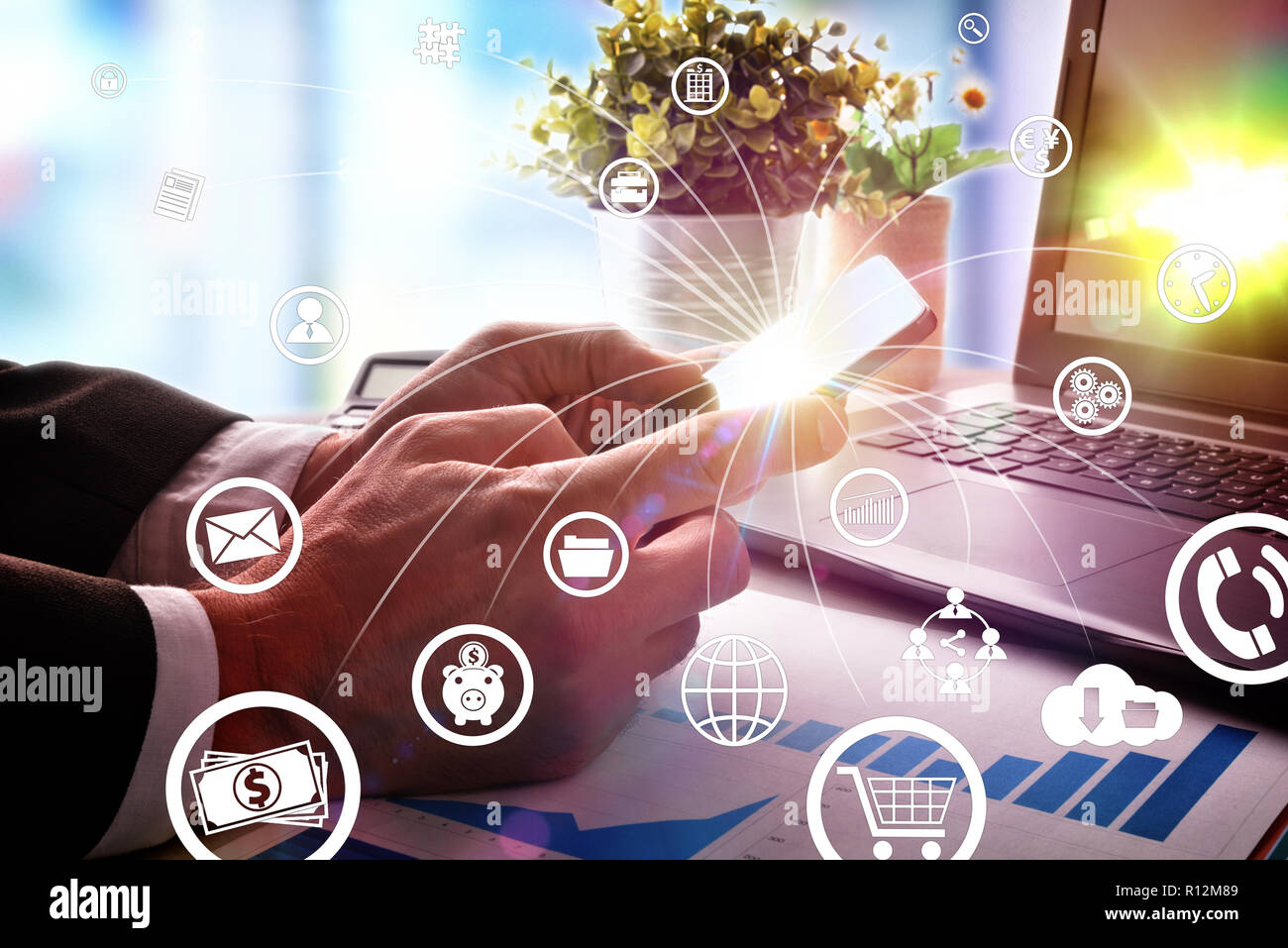 Concept of communication and internet in business with businessman with smartphone in hand at an office table and representative icons. Stock Photo