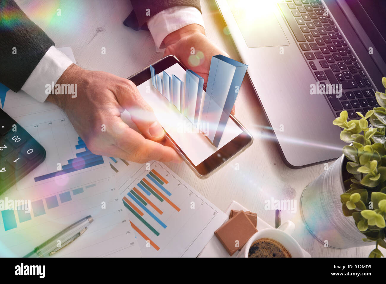 Virtual graphic representation on mobile in the hands of a businessman at the table in an office. Success concept in a business. Stock Photo