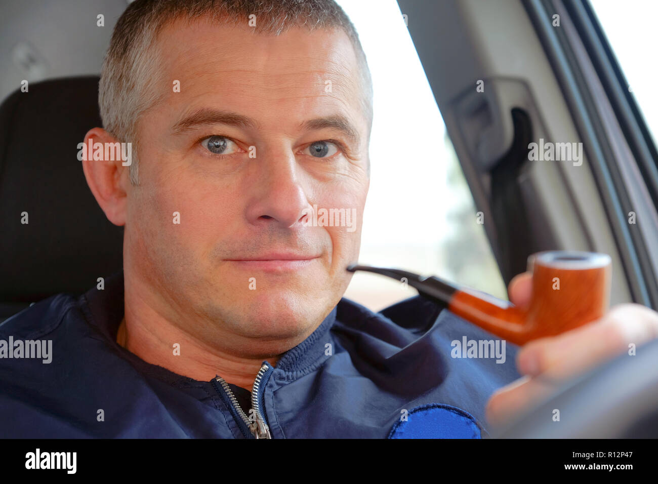 The man in the car driving. Tobacco pipe in hand. Stock Photo
