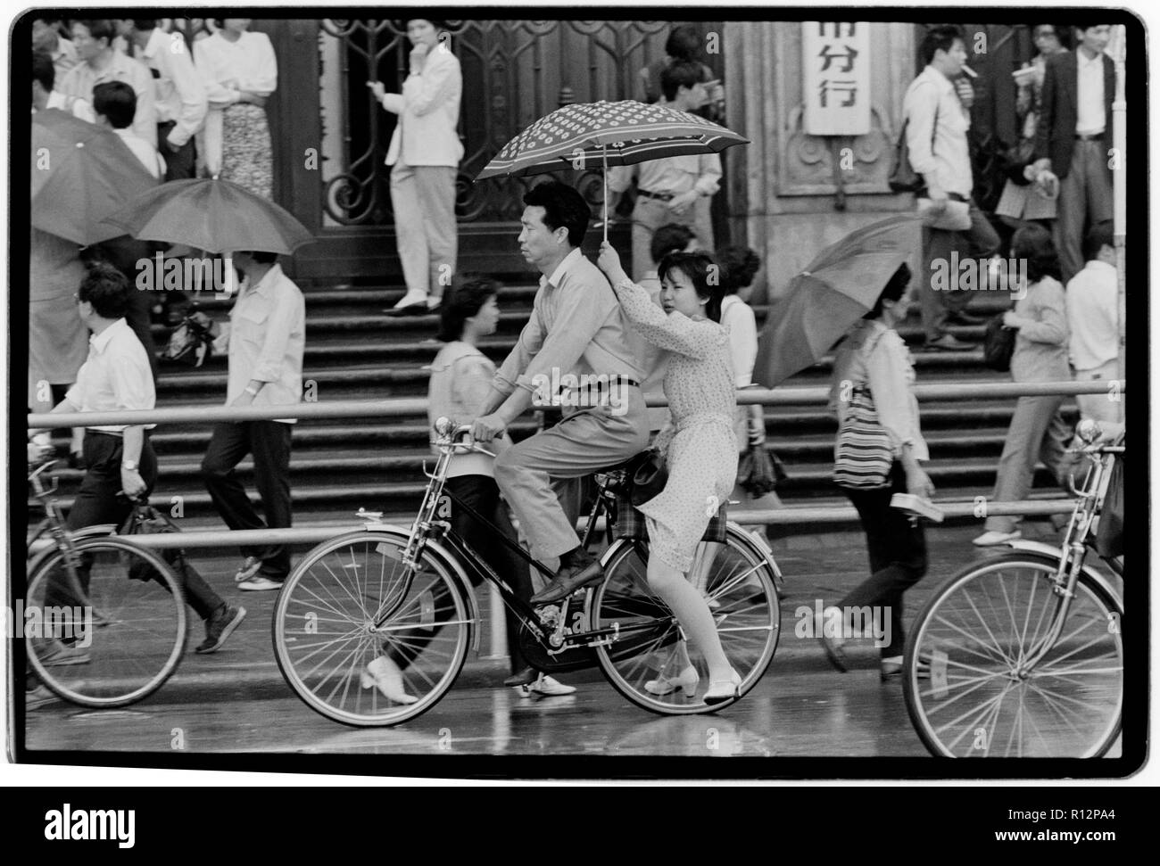 China Shanghai a few days after the massacre in Tiananmen Square in June 1989. Scans made in 2018 Men and wonen on bicycles in Shanghai in the rain. Stock Photo