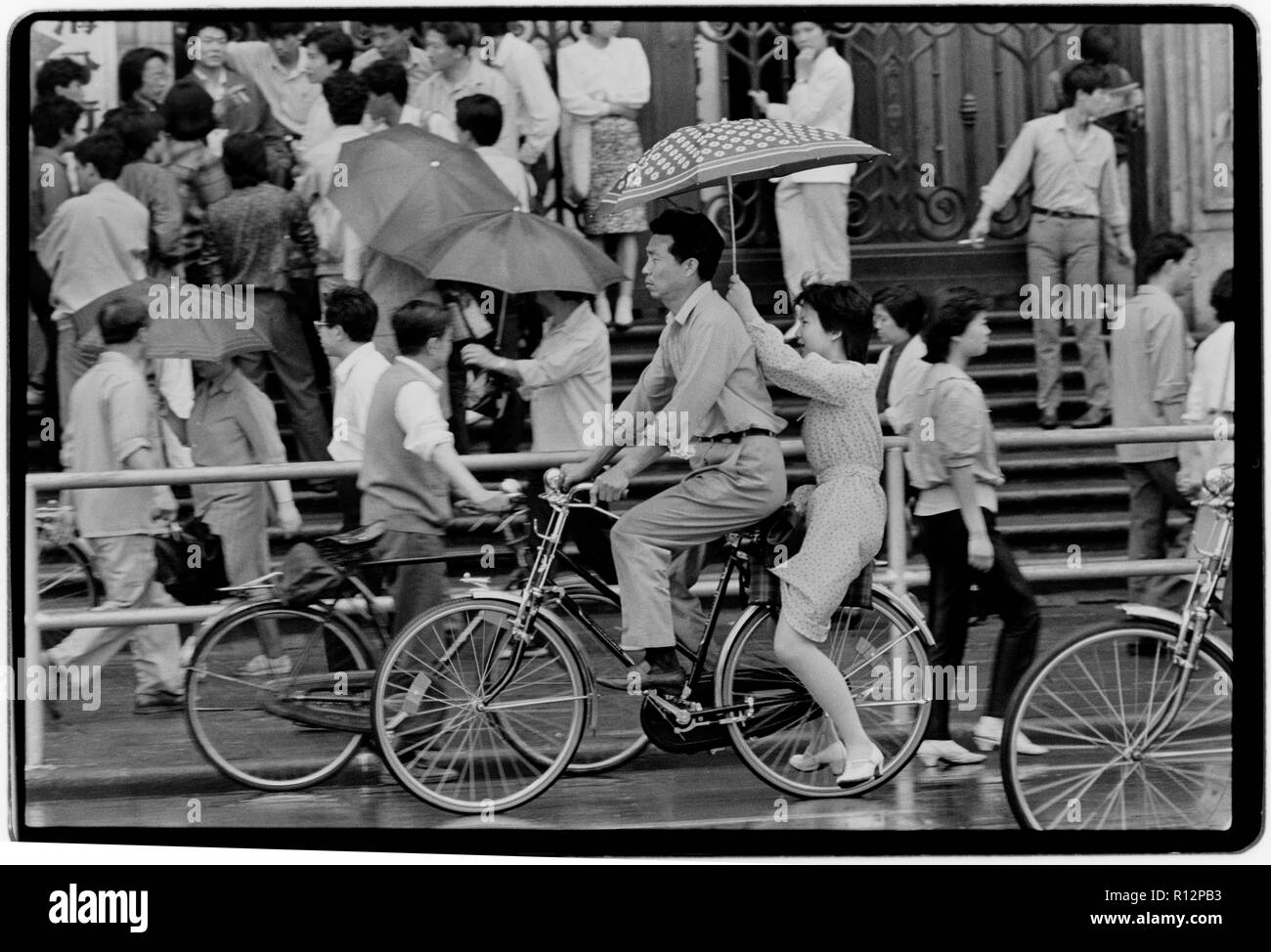 China Shanghai a few days after the massacre in Tiananmen Square in June 1989. Scans made in 2018 Men and wonen on bicycles in Shanghai in the rain. Stock Photo