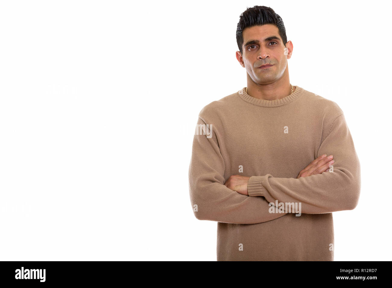 Studio shot of young muscular Persian man with arms crossed Stock Photo
