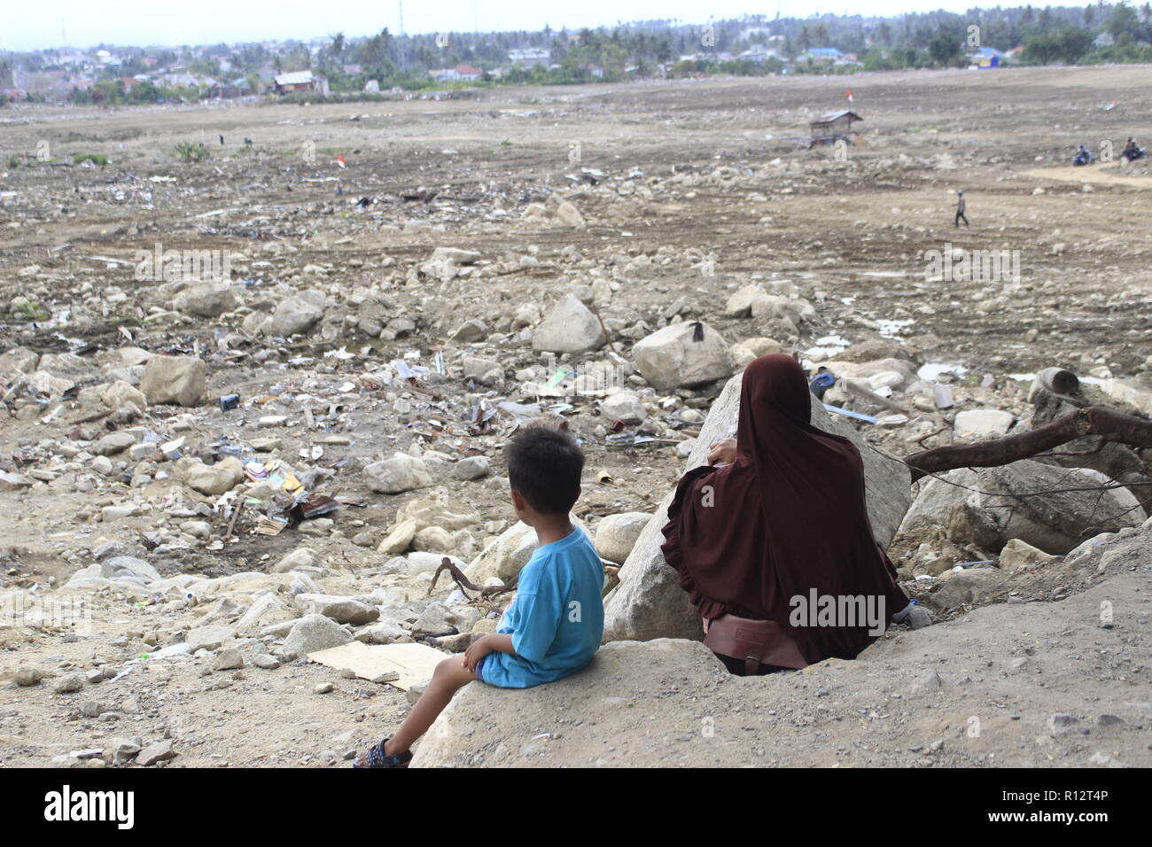 November 1, 2018 - Palu, Central Sulawesi, Indonesia - A women and kid are seen seated at the site where the earthquake happened..A deadly earthquake measuring 7.5 magnitude and a tsunami wave destroyed the city of Palu and much of the area in Central Sulawesi. The death toll was 2088, around 5000 people were seriously injured and some 62,000 people were displaced. (Credit Image: © Risa Krisadhi/SOPA Images via ZUMA Wire) Stock Photo