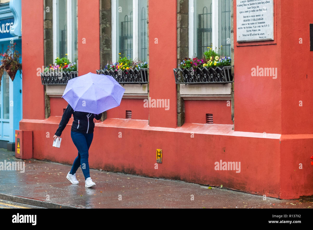 Skibbereen, West Cork, Ireland. 9th Nov, 2018. A shopper braves the elements in Skibbereen.  This afternoon will see a continuation of strong winds, which will reach gale force on the coasts. Highs today of 9 to 13°C. Credit: Andy Gibson/Alamy Live News. Stock Photo