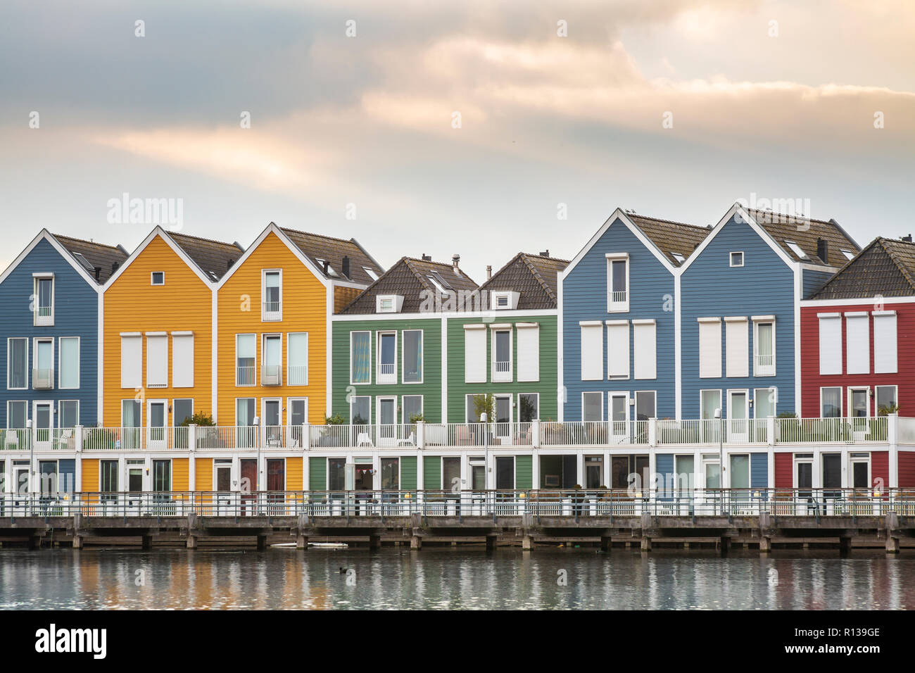 Dutch, modern, colorful vinex architecture style houses at waterside during dramatic and clouded sunset. Houten, Utrecht. Stock Photo