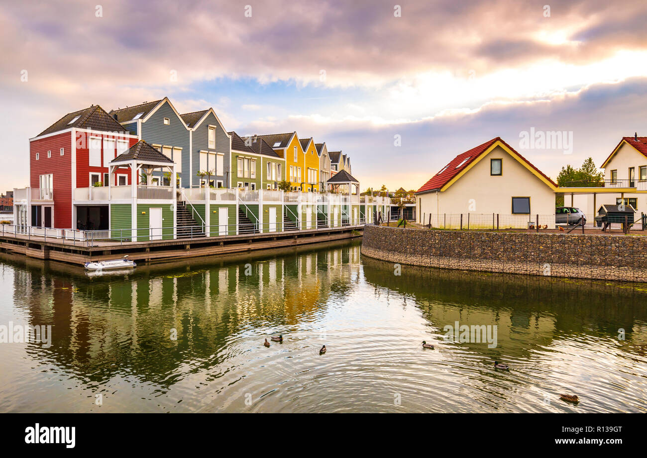 Dutch, modern, colorful vinex architecture style houses at waterside during dramatic and clouded sunset. Houten, Utrecht. Stock Photo