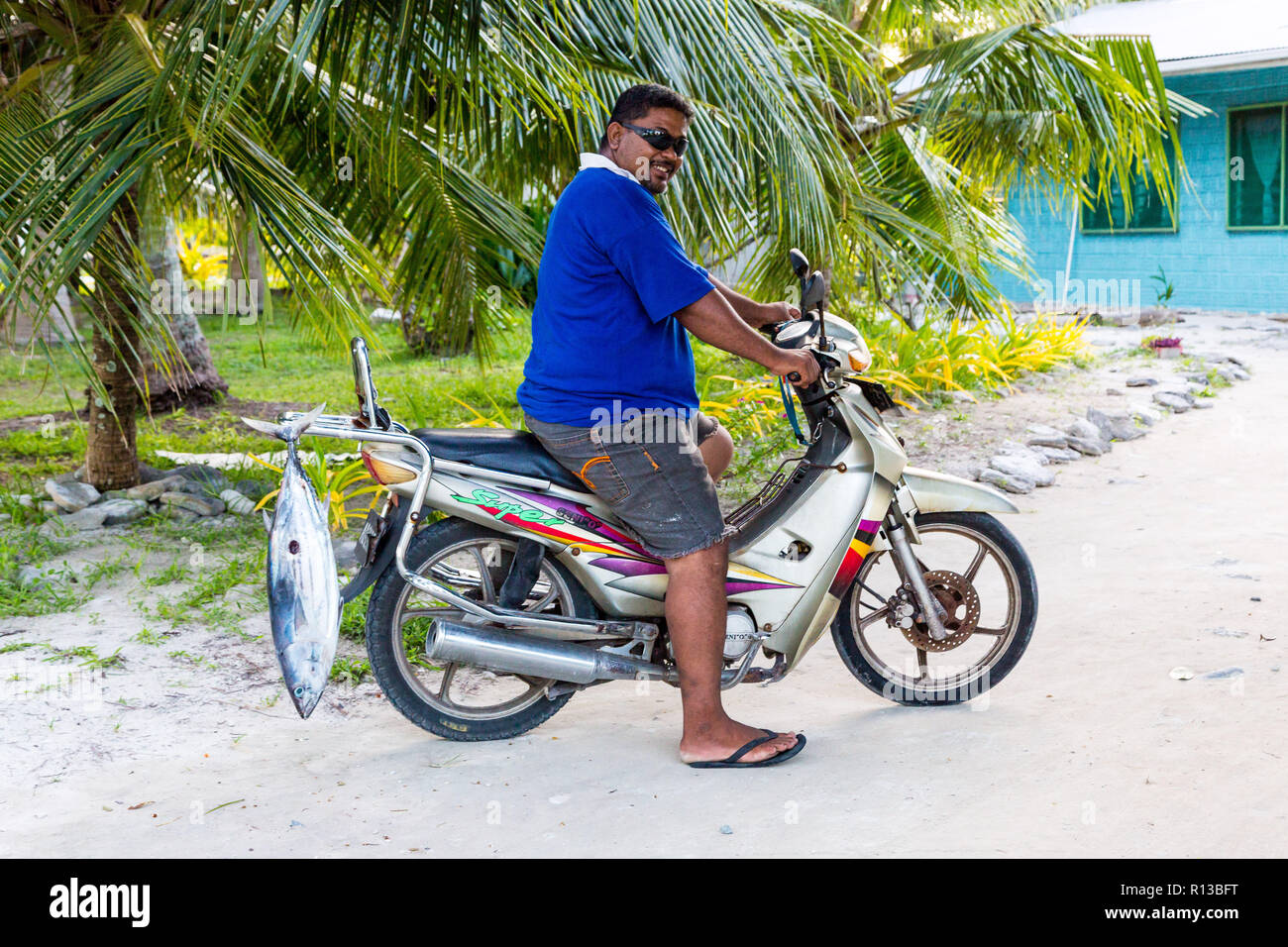 Vaiaku, Tuvalu: A local native Polynesian man on a motorcycle/motorbike with a tuna fish catch. Fongafale motu, Funafuti atoll, Polynesia, Oceania. Stock Photo