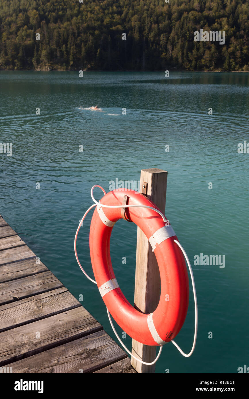 Lake 'Alpsee' with the bathing jetty of the Alpseebad and a lifebuoy on a warm sunny evening in late September. Schwangau, Füssen, Bavaria, Germany Stock Photo