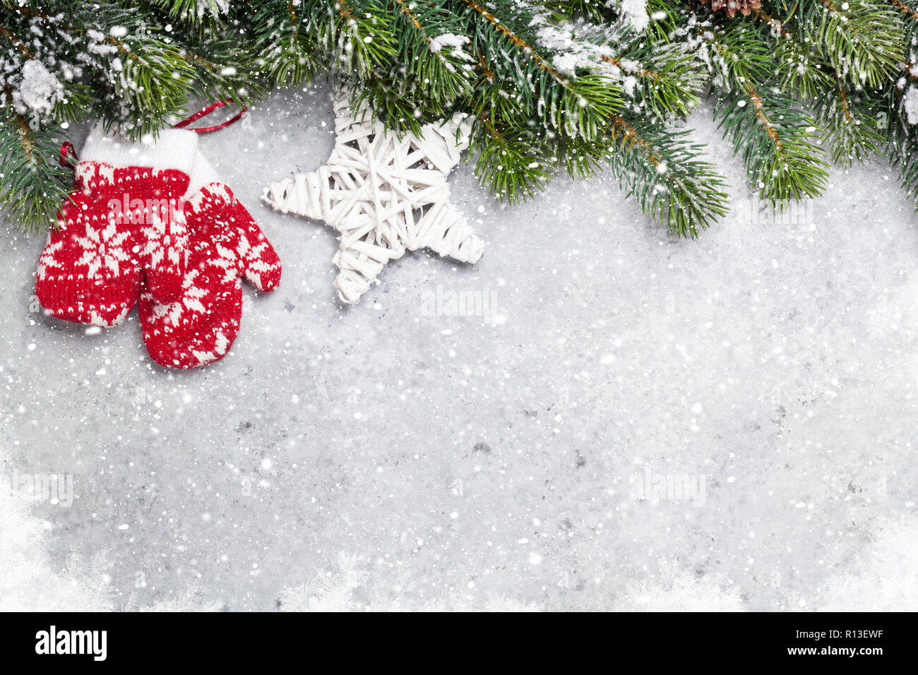 Christmas fir tree branch covered by snow and decor on stone background ...