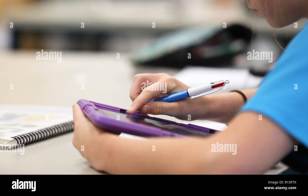 Student browsing the net using a purple tablet digital information technology tool devise to reseach during class time lesson at a modern high school  Stock Photo